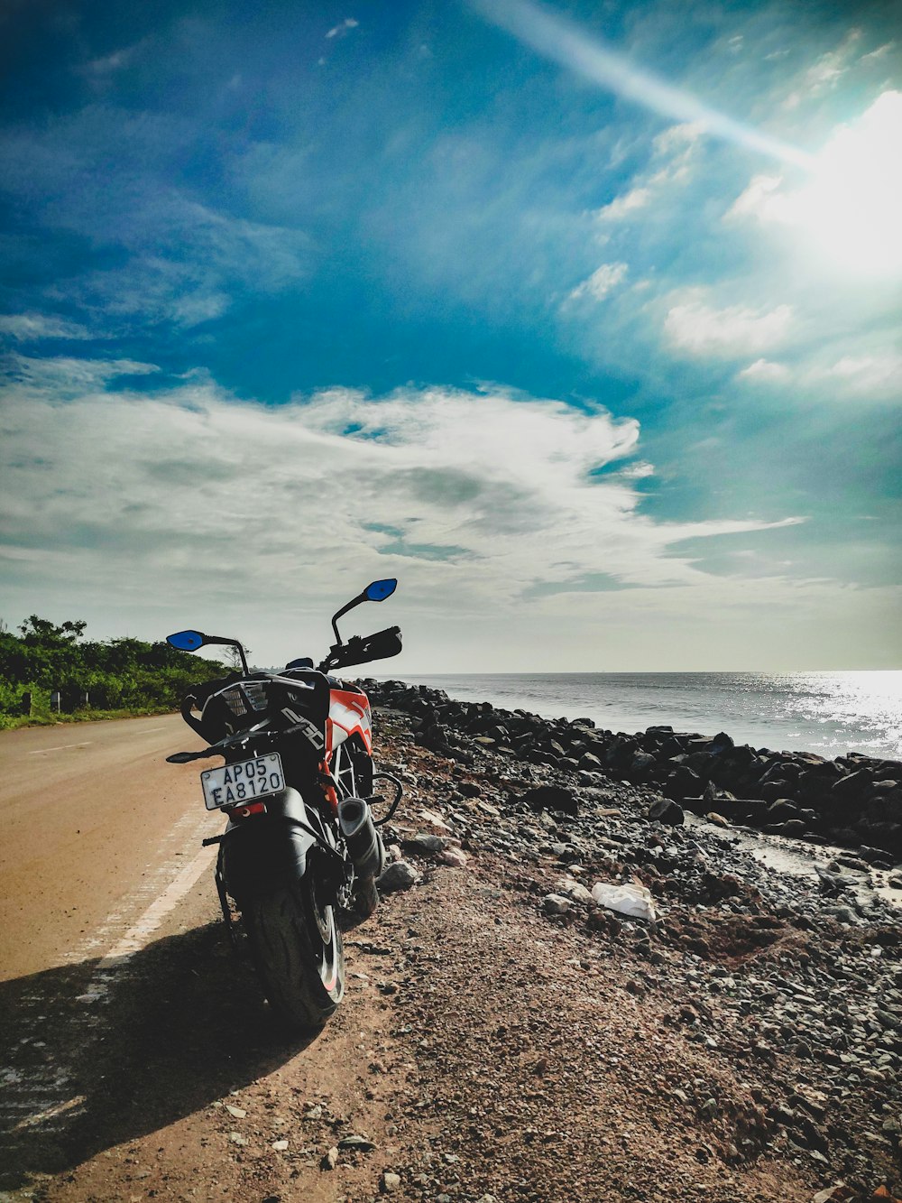 a motorcycle parked on the side of a road near the ocean