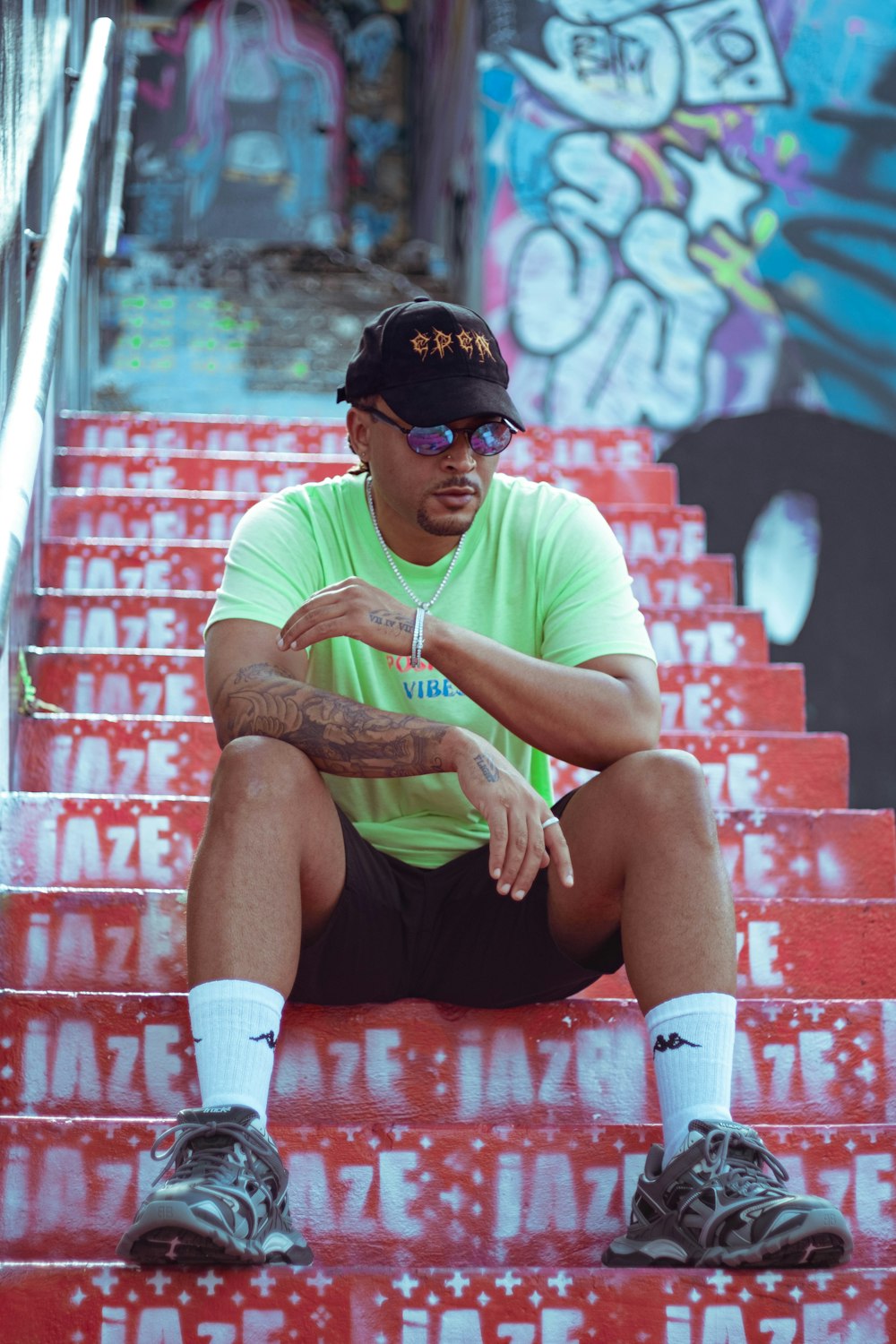 Homme en t-shirt à col rond vert et short noir assis sur un banc en béton rouge