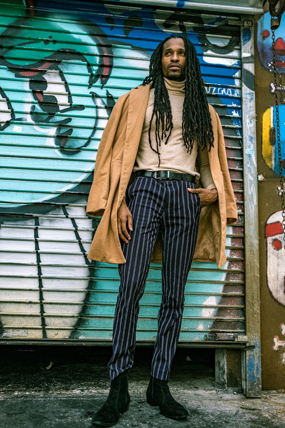 woman in brown coat and black and white striped pants standing beside white metal roll up