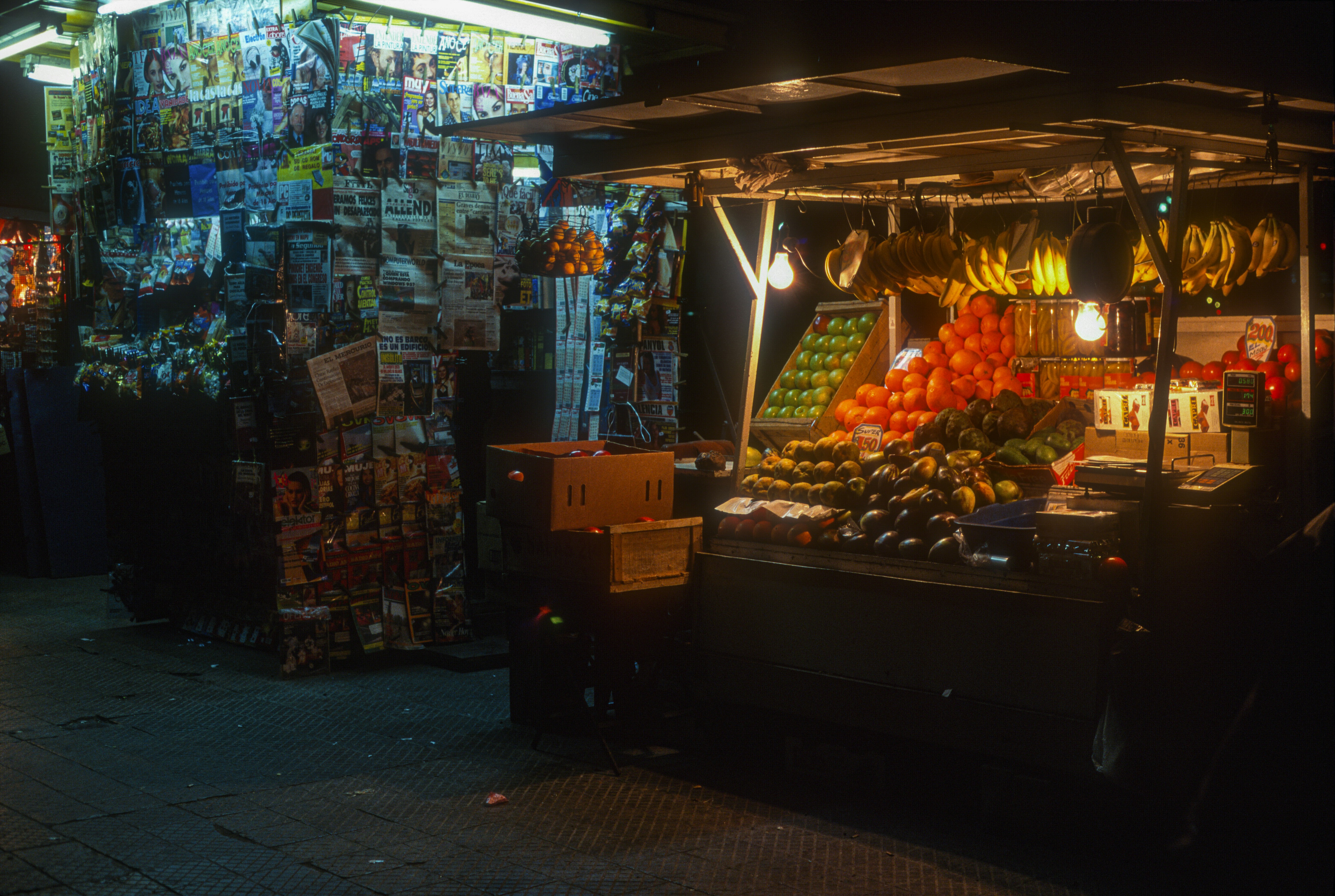 A cool little night market and news stand in Santiago. -- Shot on slide film, Canon A2E, 1995, scanned on Nikon CoolScan 4000