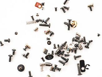 Stainless steel screws and hardware pieces laid out on a metal workbench.