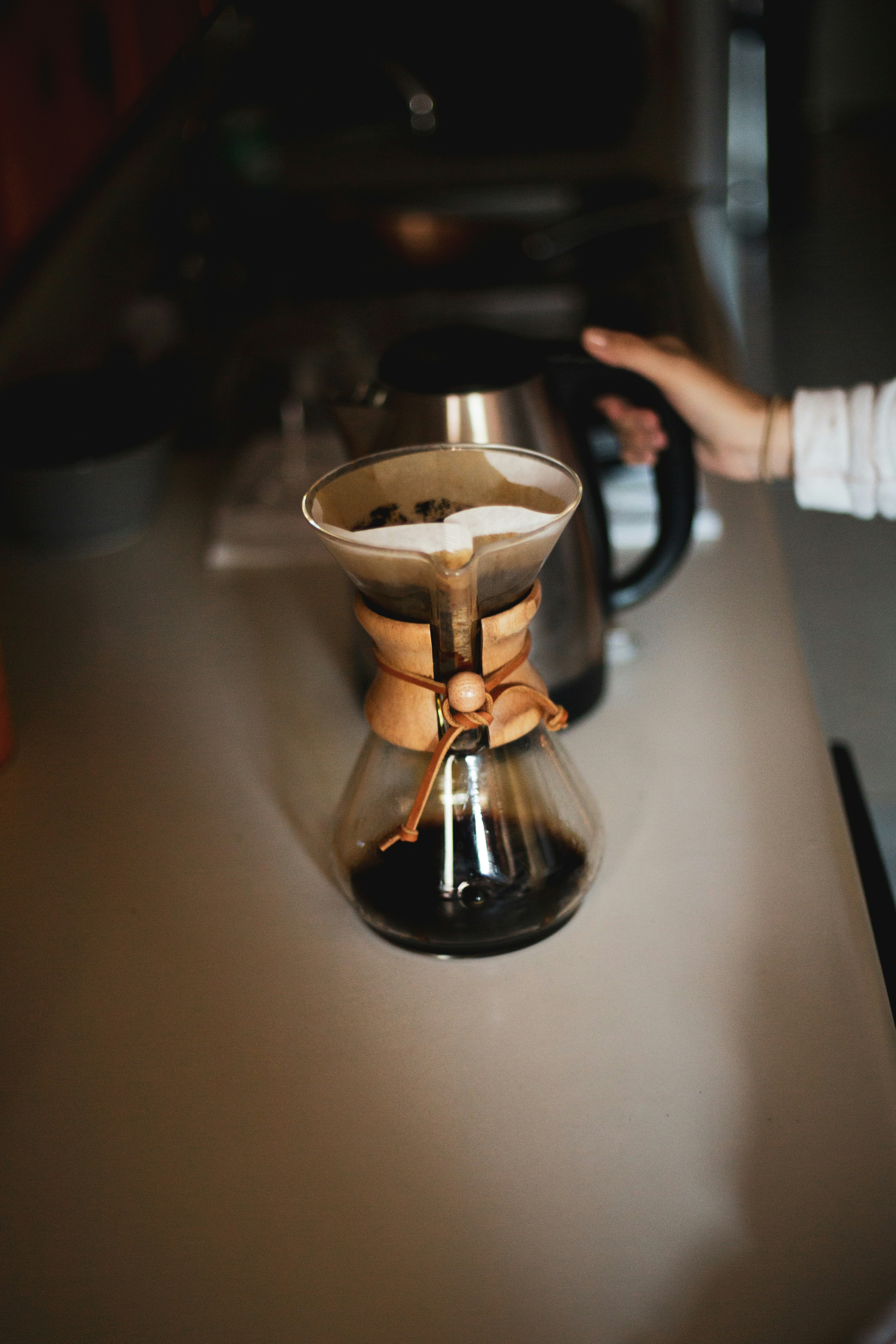 Person gießt Kaffee auf silberne Tasse