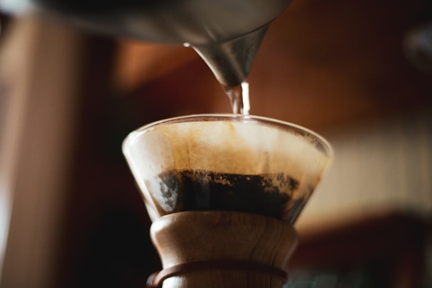 Close-up of a V60 pour-over coffee dripper with fresh coffee dripping into a glass carafe.