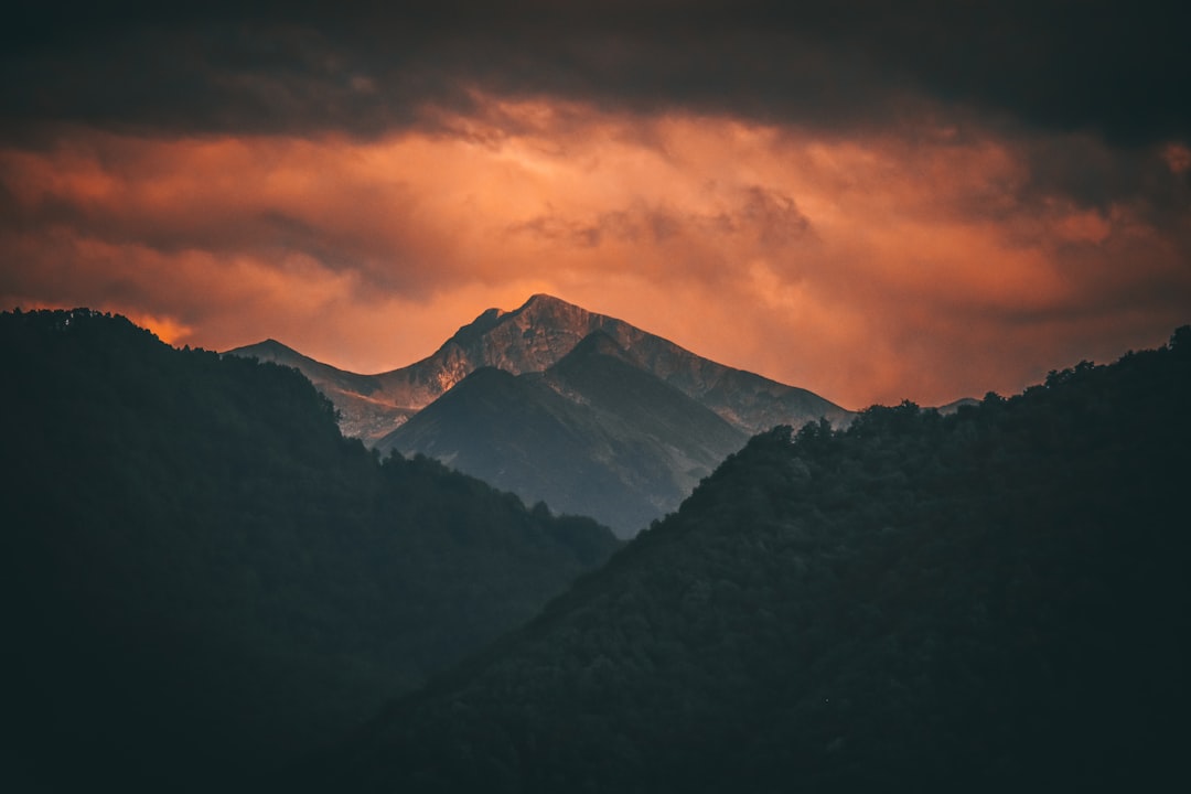 black and white mountains under orange and gray cloudy sky