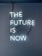 A neon sign with the phrase 'THE FUTURE IS NOW' mounted on a dark blue wall. The letters are glowing in a bright white light, with visible wires connecting them.