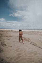 topless man in black shorts sitting on brown sand during daytime
