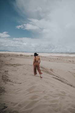 topless man in black shorts sitting on brown sand during daytime