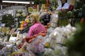a woman standing in front of a display of fruits and vegetables