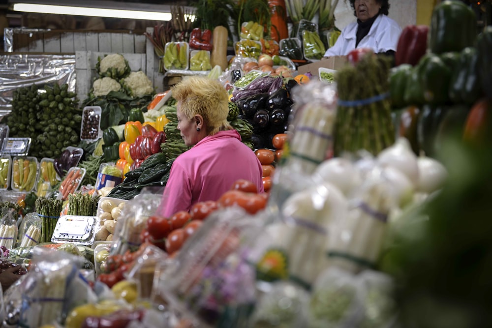 a woman standing in front of a display of fruits and vegetables