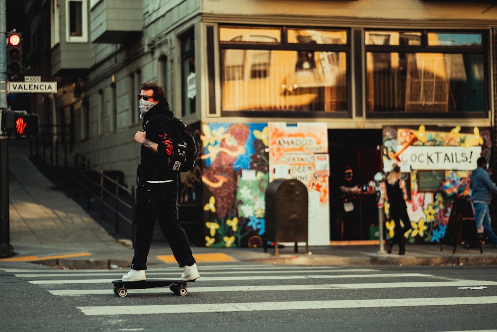 man in black jacket and black pants walking on pedestrian lane during daytime