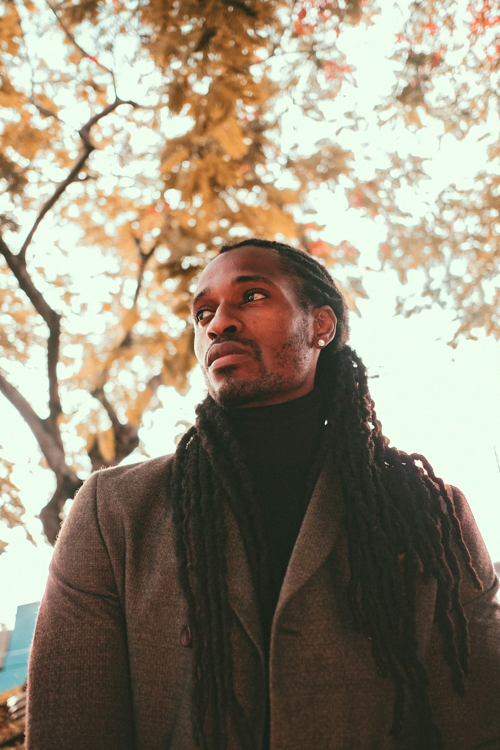 man in brown coat standing under tree during daytime