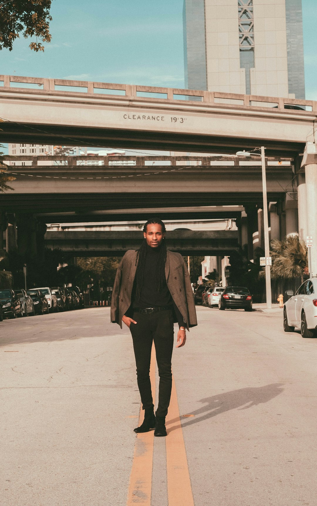 woman in black coat standing on sidewalk during daytime