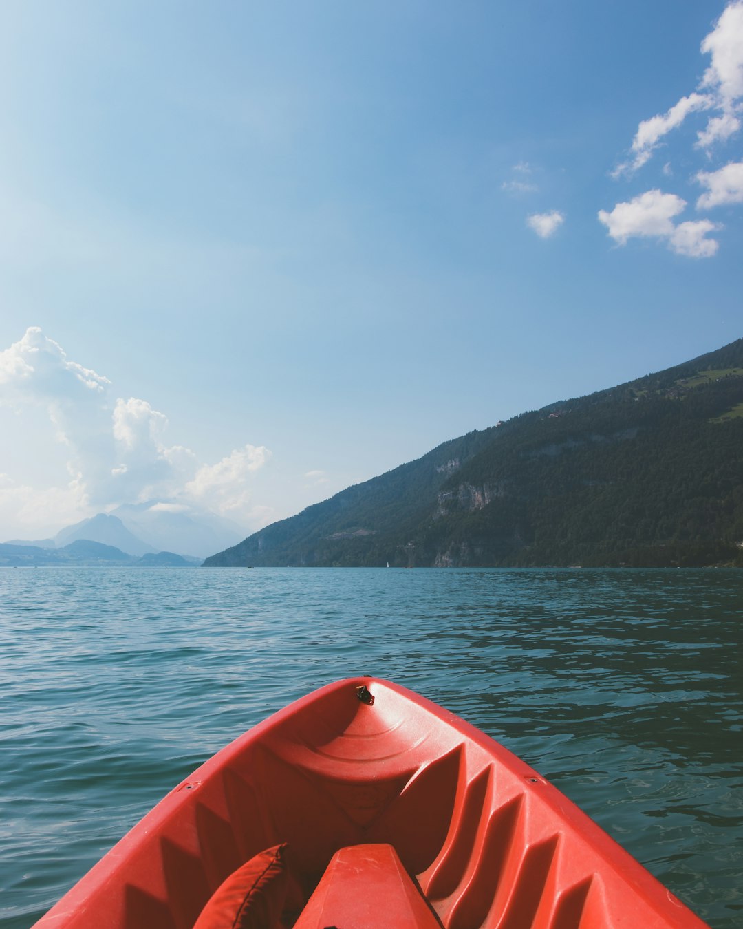 red kayak on sea near mountain under blue sky during daytime