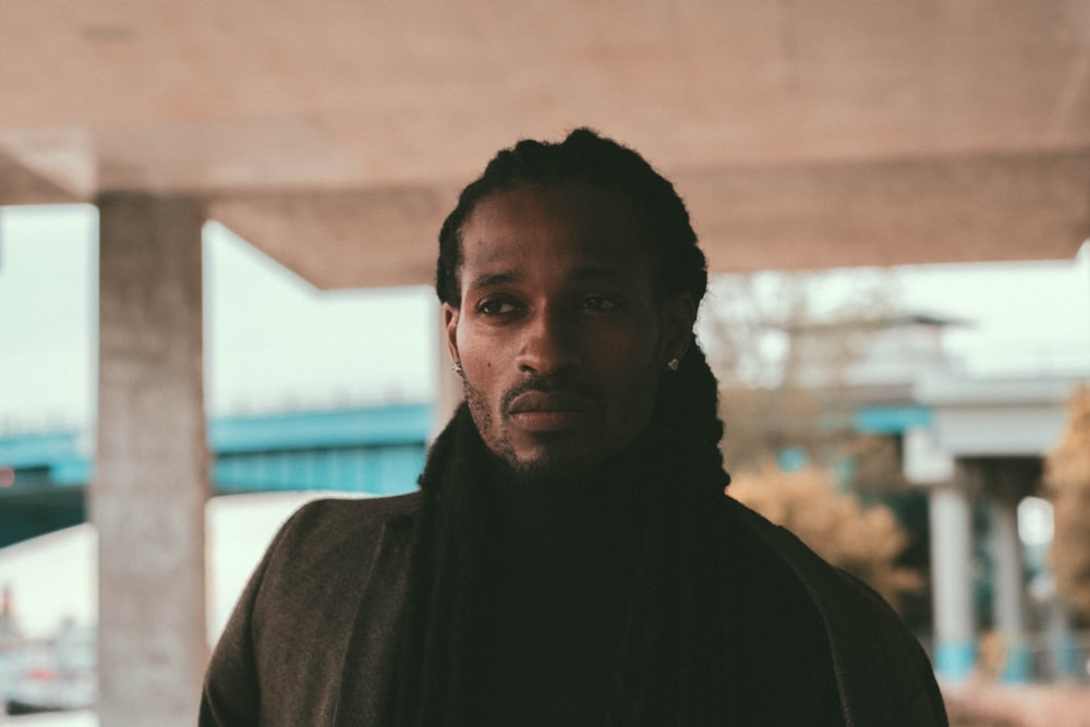 man in black hoodie standing near brown wall