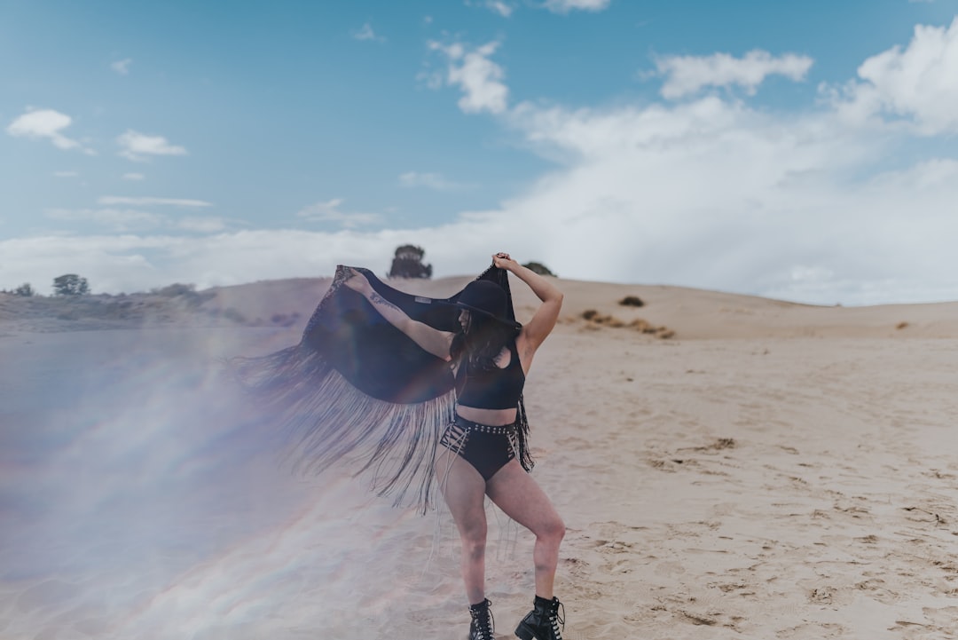 woman in black sports bra and red shorts standing on white sand during daytime