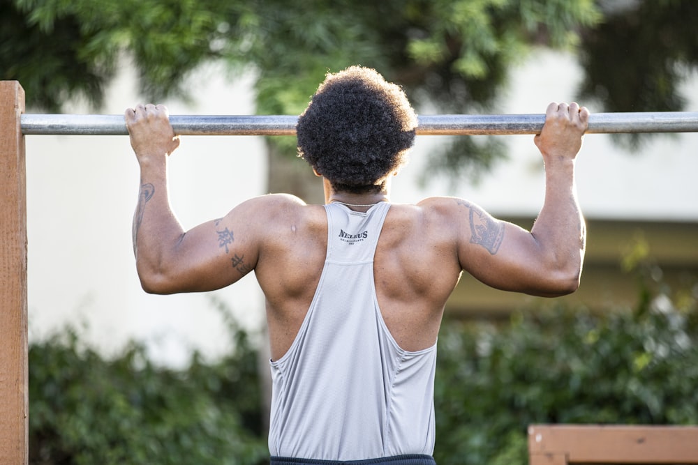 man in gray tank top holding gray metal bar