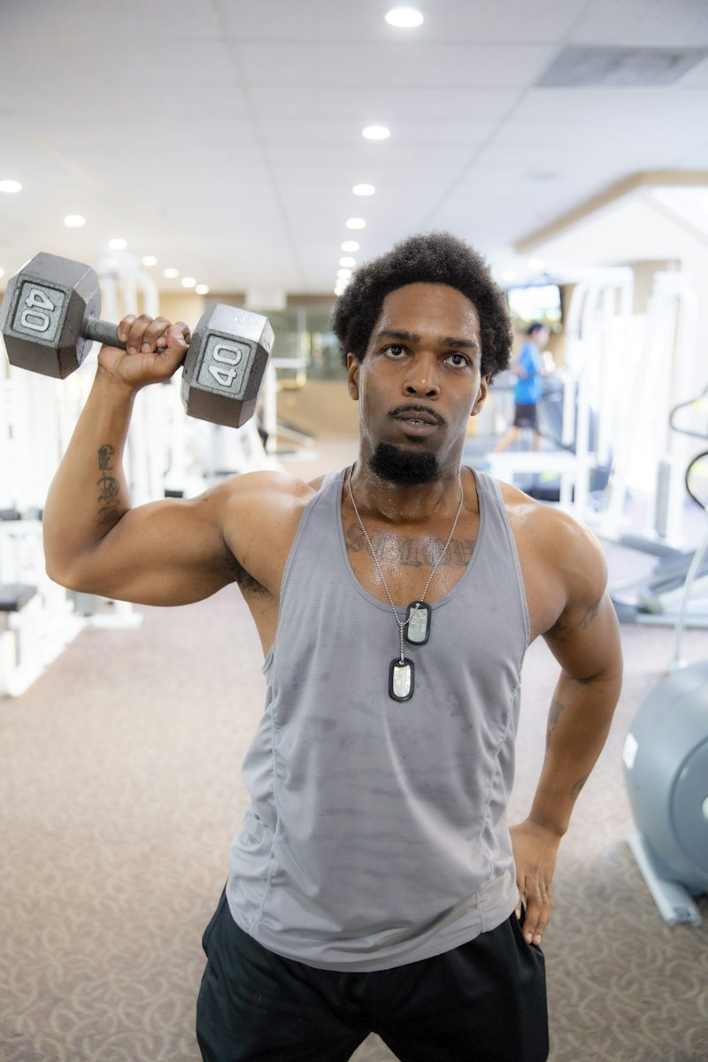 Marcus Okafor, Head Trainer at FitForge, pressing a dumbbell on the gym floor