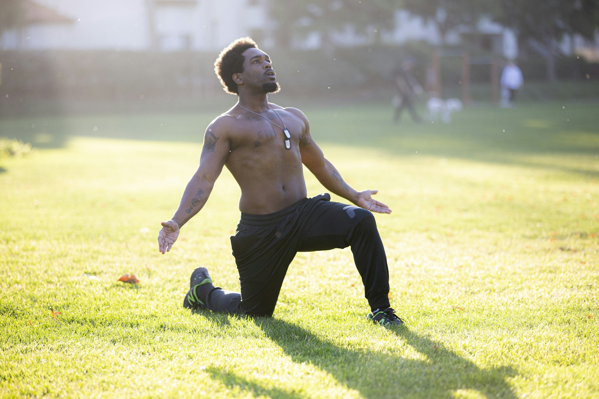 topless man in black pants and black shoes running on green grass field during daytime