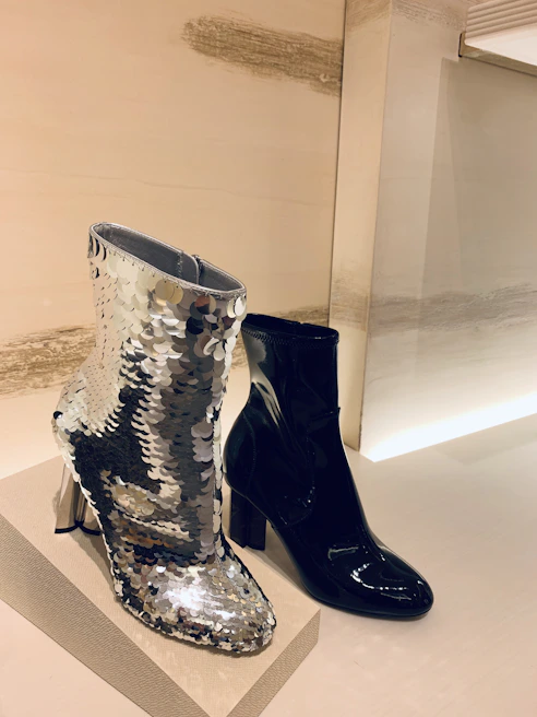Minimalist black ankle boots displayed against a soft nude fabric backdrop