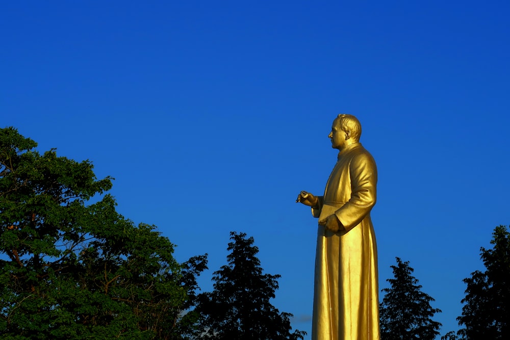 gold statue of a man holding a book