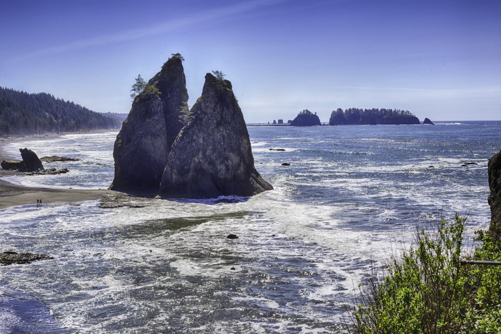 brown rock formation on sea under blue sky during daytime