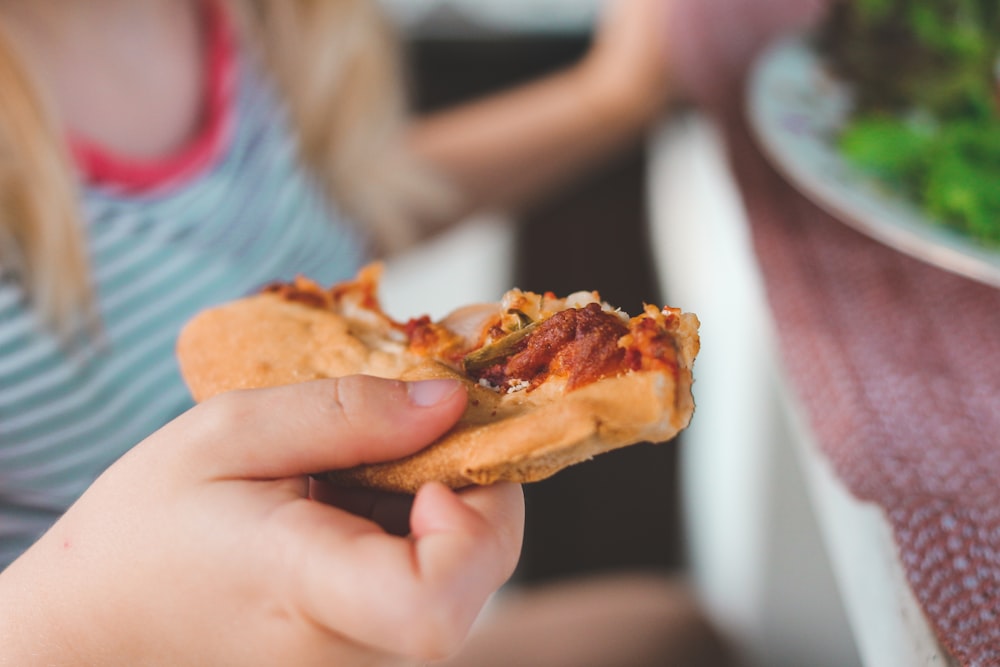 person holding burger with cheese