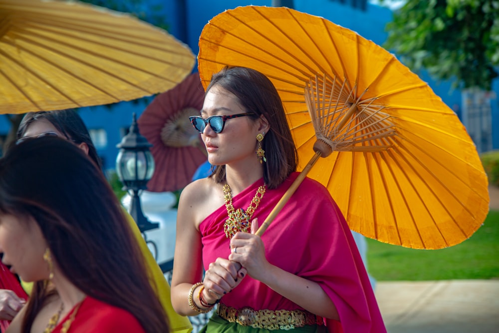 Mujer en vestido rojo con gafas de sol sosteniendo paraguas