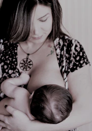 A lactation consultant gently guiding a mother during a breastfeeding session.