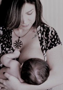 A caring lactation consultant gently supporting a mother breastfeeding her baby in a cozy home setting