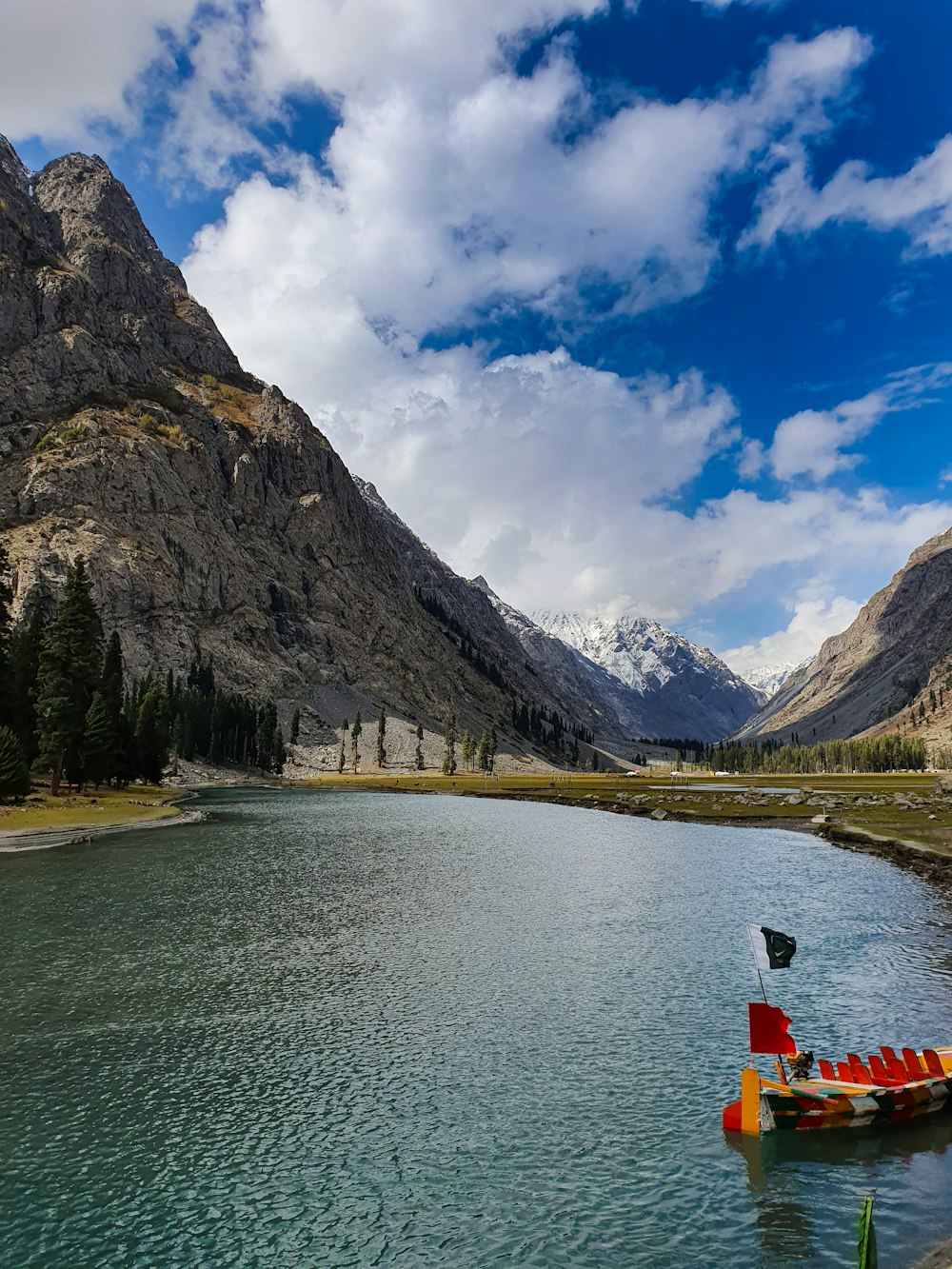 green trees near lake and mountain under blue sky during daytime