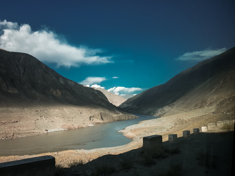 brown mountain near body of water under blue sky during daytime