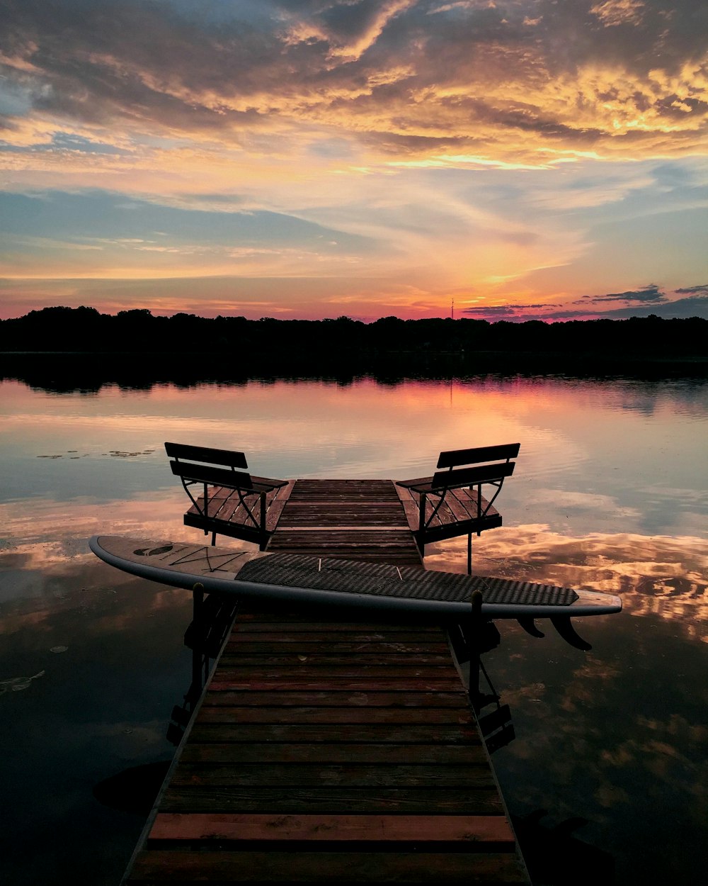 brown wooden bench on dock during sunset