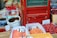 A variety of dried goods displayed in open sacks and boxes at a marketplace. Signs with handwritten prices in Chinese are visible on each sack, indicating different types of dried produce. The setting appears to be an outdoor market, possibly in an Asian country. The collection includes dried fruits, nuts, and seeds, showcasing a colorful assortment.