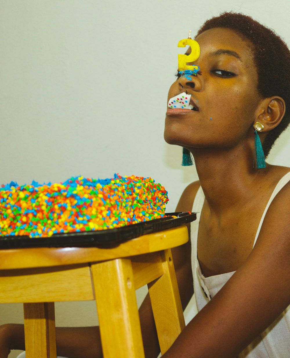 Femme en débardeur blanc avec des paillettes de bonbons multicolores sur son visage