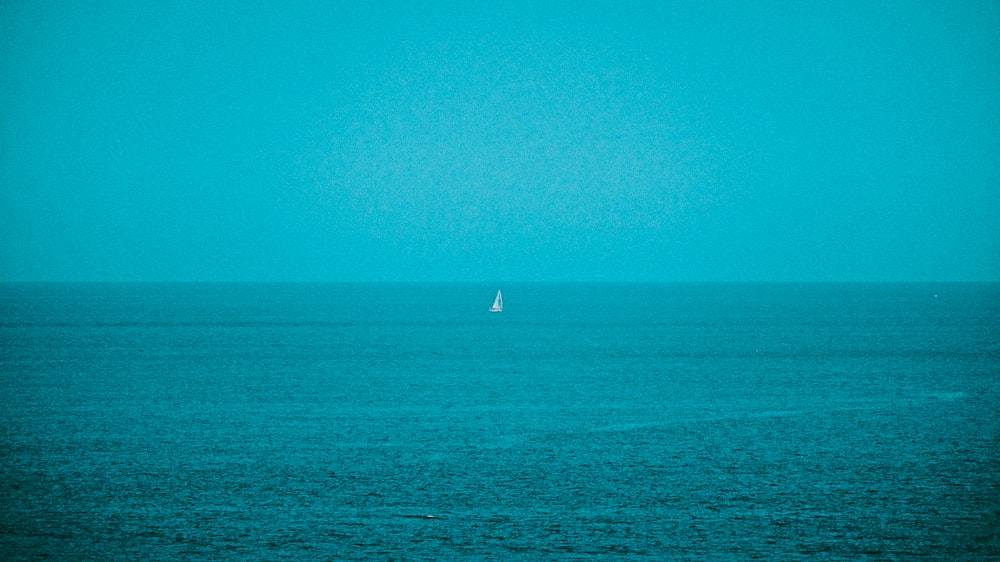 a lone sailboat in the middle of the ocean