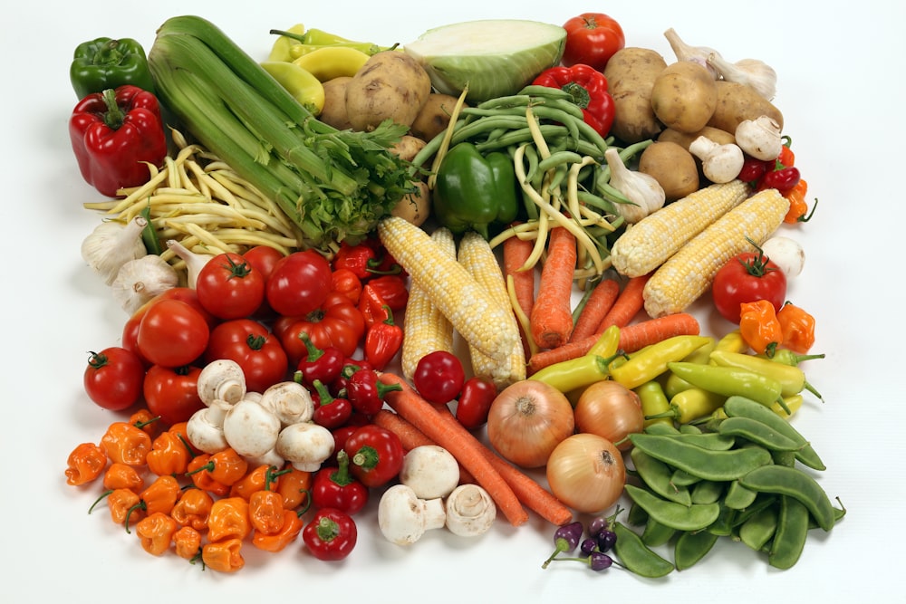 Una pila de diferentes tipos de verduras sobre una superficie blanca