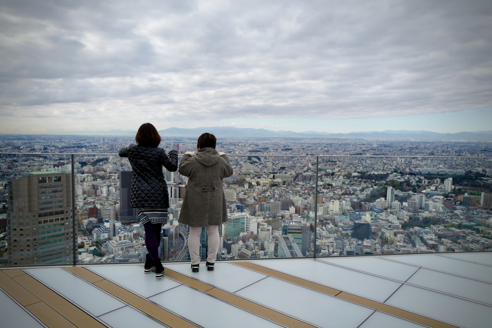 man in gray jacket standing on top of building looking at city during daytime