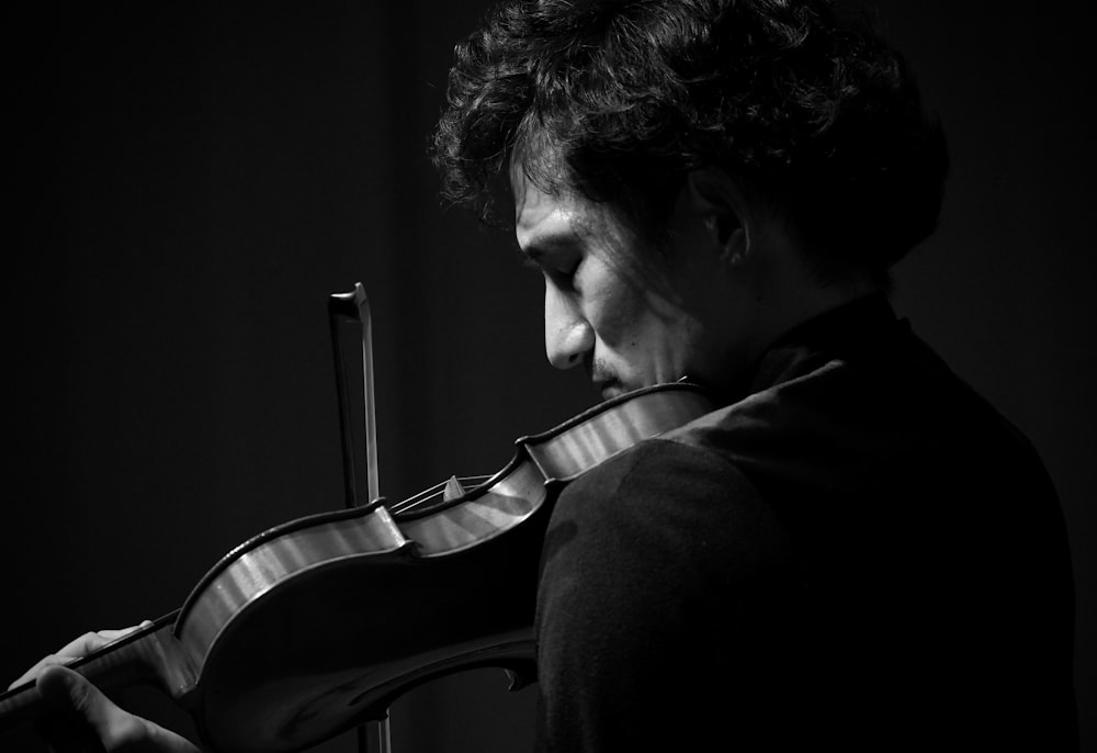 man playing violin in grayscale photography