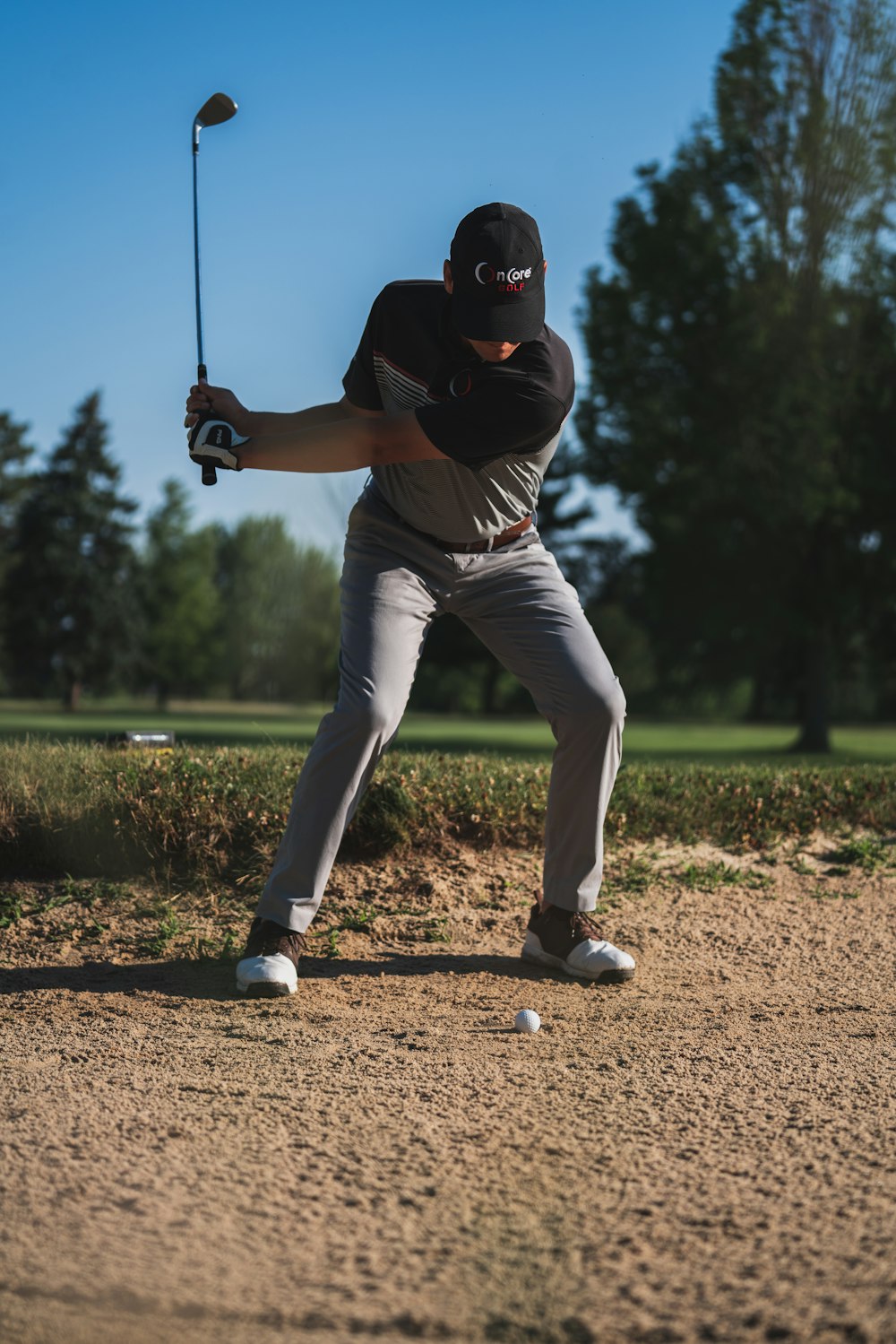 man in black shirt and white pants playing golf during daytime