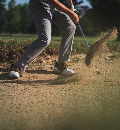 person in black t-shirt and white pants holding golf club