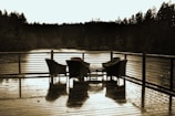 Wooden deck overlooking a calm loch with a pair of chairs inviting quiet reflection.