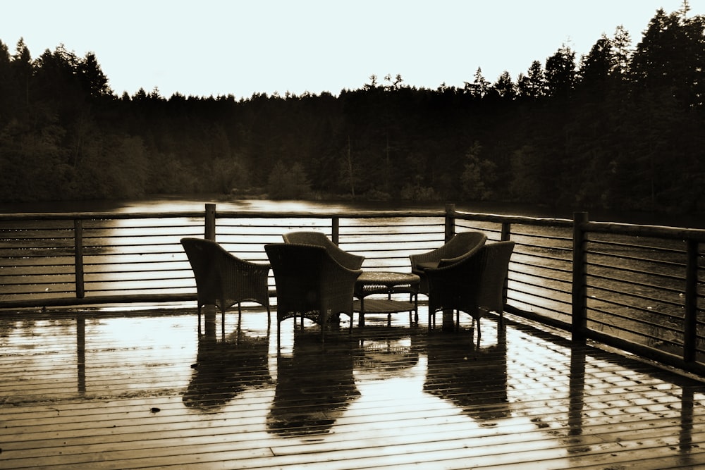 Graustufenfoto von zwei Holzstühlen auf Holzsteg