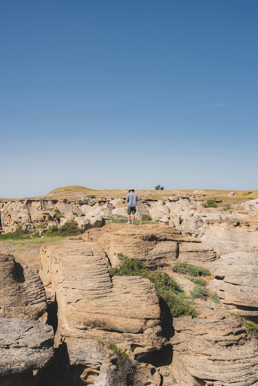 man in white shirt standing on brown rock formation during daytime