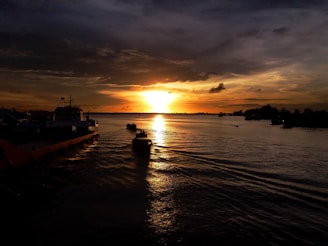 silhouette of boat on sea during sunset