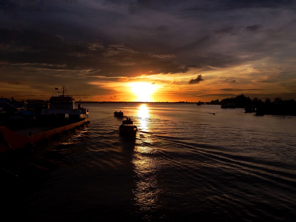 silhouette of boat on sea during sunset