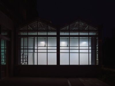 Evening shot of the gallery exterior glowing warmly through large windows.