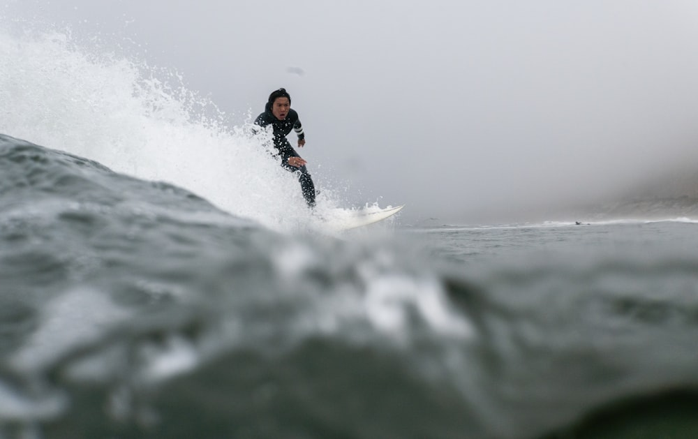 man in black and orange wet suit surfing on sea waves during daytime