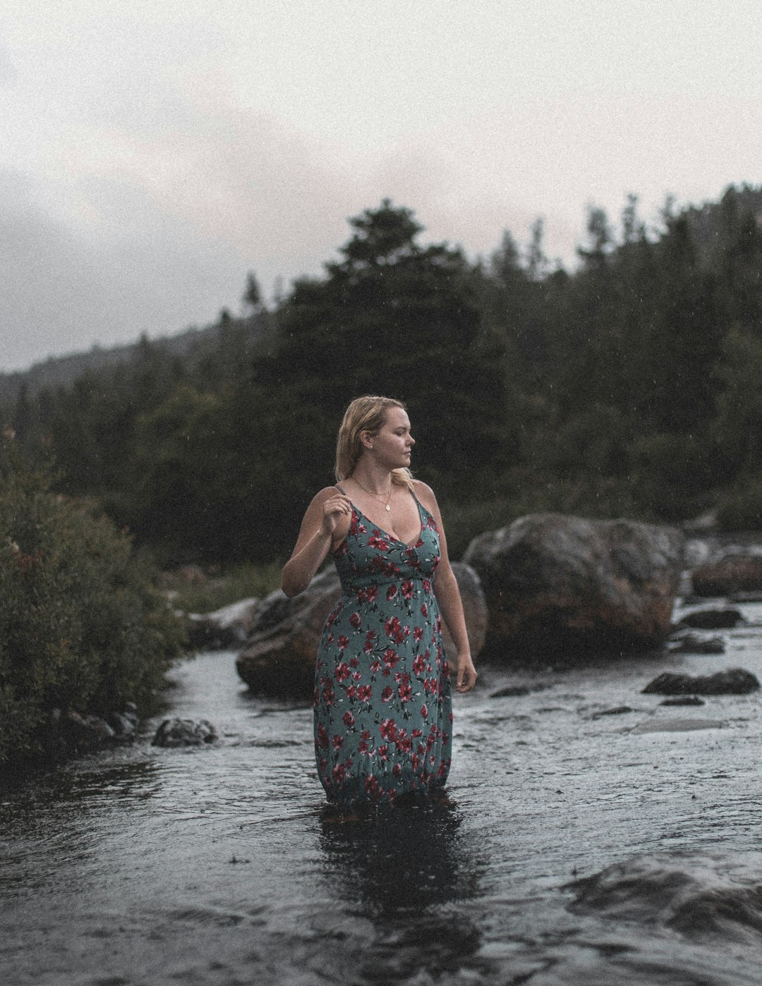 woman in blue and white floral spaghetti strap dress standing on river during daytime