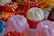Assorted jelly molds with a glossy texture are arranged on a surface. The molds are in various colors, including pink, white, and orange, creating a vibrant and playful appearance. The translucent nature of the jellies allows light to enhance their bright hues.