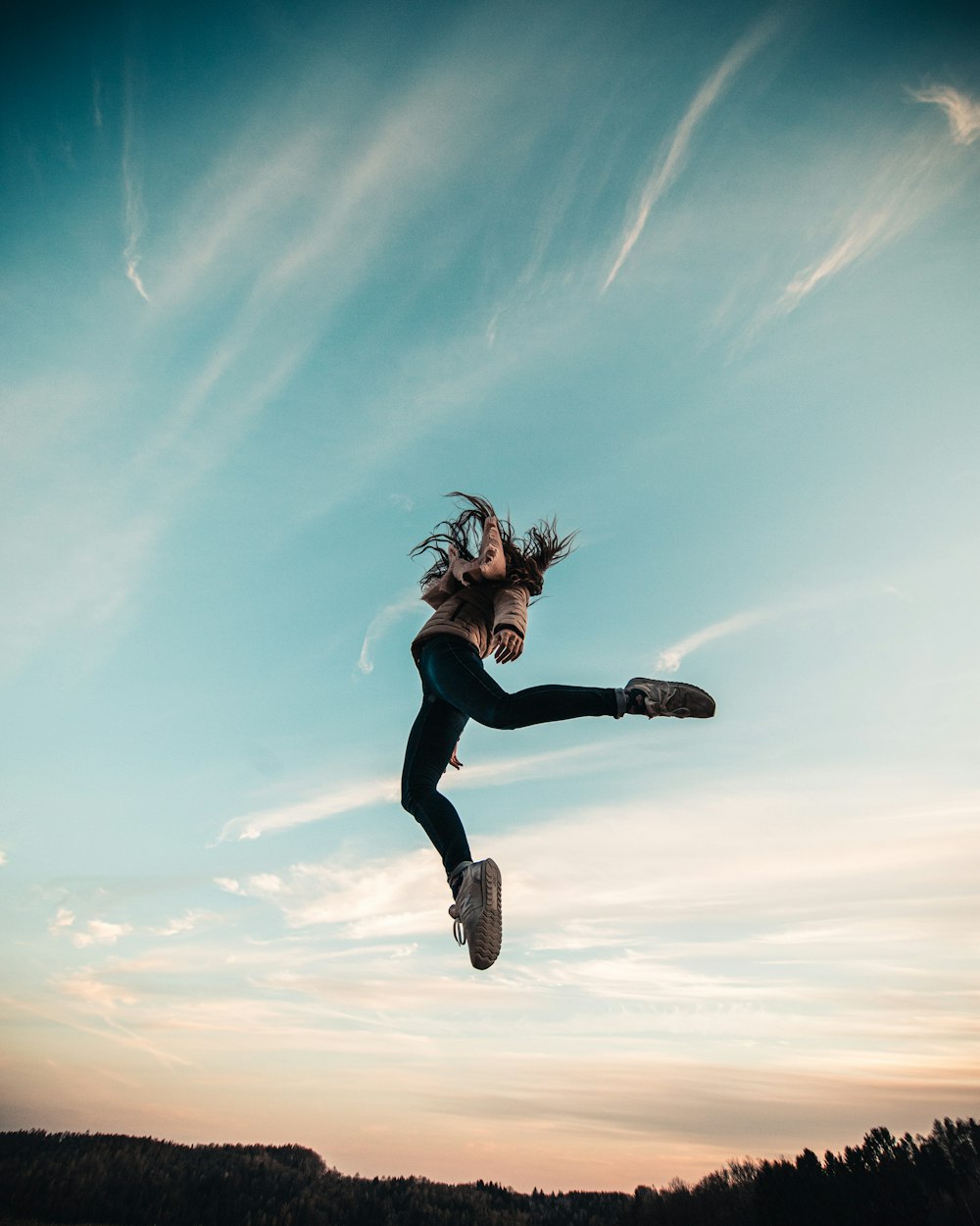 woman in black long sleeve shirt and black pants jumping under blue sky during daytime